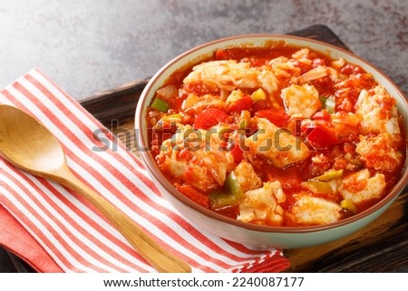 Ajoarriero is a traditional Spanish dish consists of shredded salt cod that's combined with tomatoes, garlic, onions, red and green peppers and potatoes closeup on the bowl on the table. Horizontal
