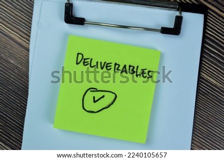 Concept of Deliverables write on sticky notes isolated on Wooden Table. Royalty-Free Stock Photo #2240105657