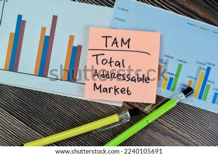 Concept of TAM - Total Addressable Market write on sticky notes isolated on Wooden Table.