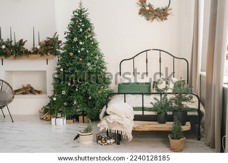 Bedroom in bright colors for celebrating the New Year. Christmas mood at home. A white bedroom and a Christmas tree.