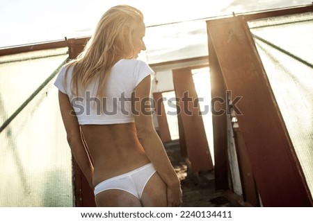 Girl in white T-shirt and panties at sunset on the roof
