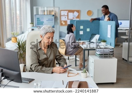 Portrait of elegant senior businesswoman working at desk in open office setting, copy space Royalty-Free Stock Photo #2240141887