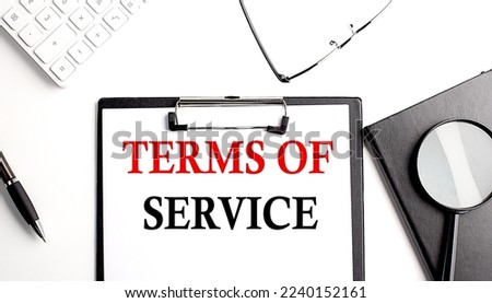 TERMS OF SERVICE text written on a paper clipboard with office tools