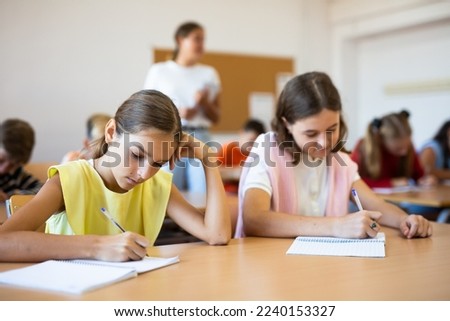 Portrait of schoolgirl who writing exercises at lesson in school