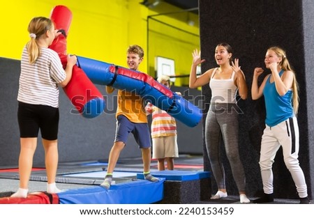 Smiling children having funny wrestling by inflatable logs in indoor amusement park