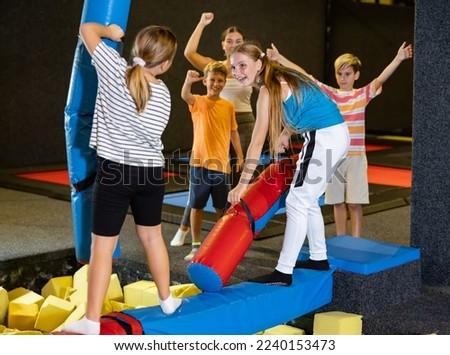 Children girls having fun and playing with inflatable sticks on the trampoline arena while spending time together on weekend