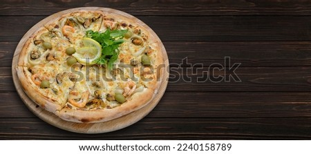 Pizza with seafood, olives and cheese, on a wooden board, on a wooden background