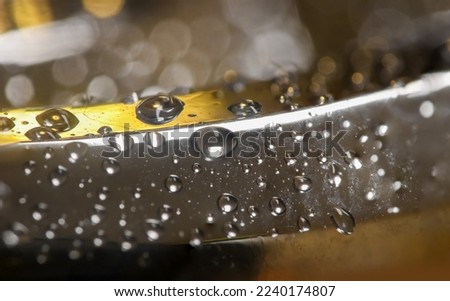 Extreme close up shot of water droplets on lady 's stainless steel bracelet. Selective focus.