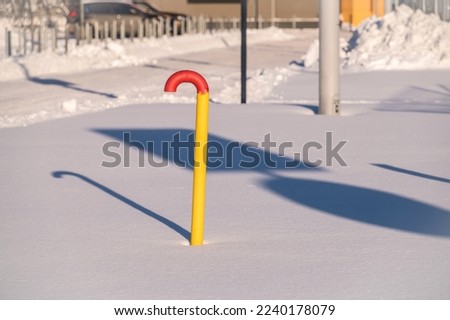 A yellow gas pipe sticks out of the snow