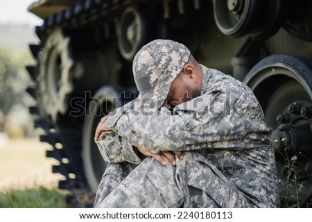 Stressed depressed crying lose war Asian man special forces soldier against on the field Mission. Commander Army soldier military defender of the nation in uniform near battle tank state of war. Royalty-Free Stock Photo #2240180113