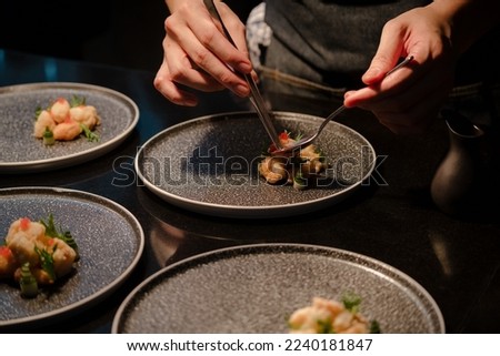 Close up of a chef's hand cooking and preparing fine dining meals. Food prepping in the kitchen. Royalty-Free Stock Photo #2240181847