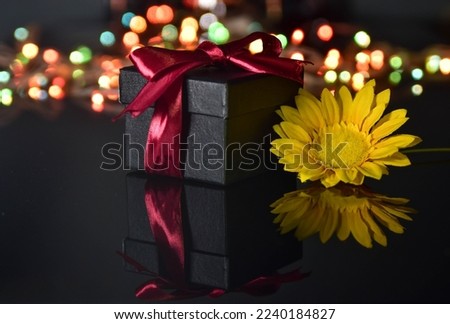 Box gift tied with red ribbon and flower on blurry colorful ligh