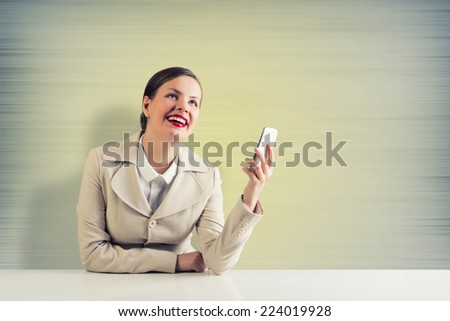 Young pretty businesswoman sitting at table with mobile phone in hand