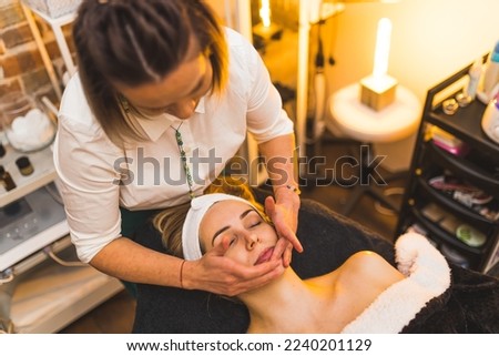 A woman getting a hand facial spa massage in a beauty salon. High quality photo