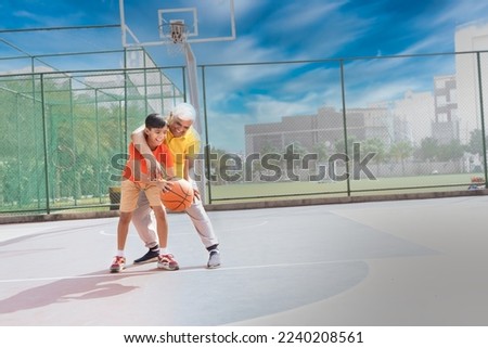 Grandfather and his grandson enjoying and playing together on basketball court. Royalty-Free Stock Photo #2240208561
