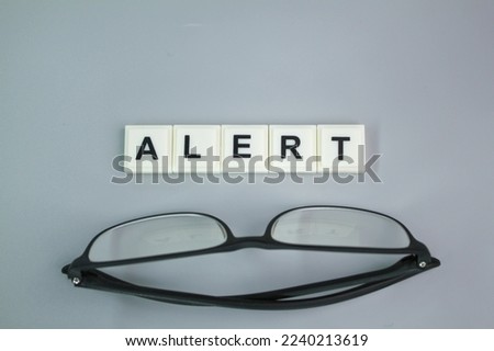 glasses with the word alert. the concept of warning or caution. exclamation mark