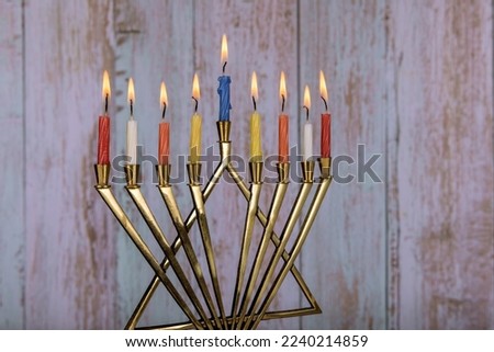Jewish holiday menorah with burning candles for Hanukkah with colorful candles.