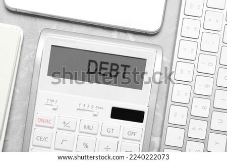 Calculator with word Debt on light grey marble table, flat lay