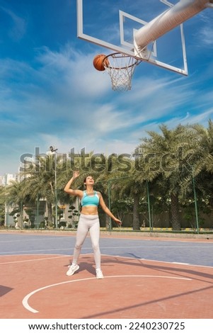 Female athlete playing basketball on a street court, dribbling and training.