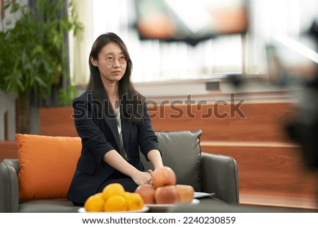  Asian anchorwoman waiting and preparing for interview in studio            