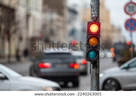 a city crossing with a semaphore on blurred background with cars in the evening streets, red light