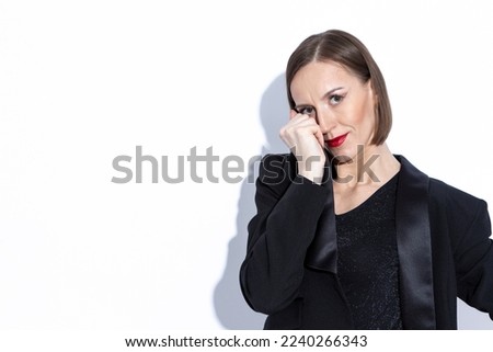 Shy Portrait of Winsome Positive Confident Caucasian Business Woman in Black Suit Posing Over White Background. Horizontal Shot