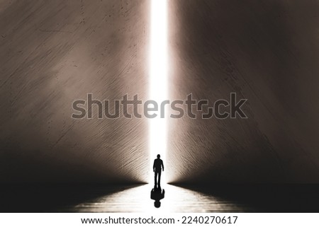 The silhouette of a man walking towards a bright light in the opened huge wall. A light in the end of a tunnel. The concept of success, freedom of choice, open mind, meditation. Royalty-Free Stock Photo #2240270617