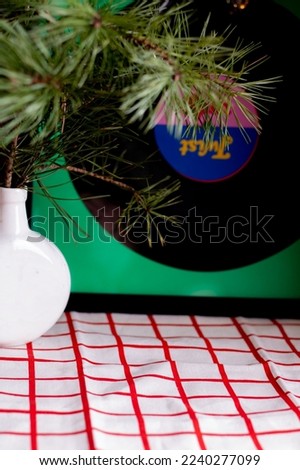 photo white and red tablecloth on the table, on it there is a white vase with a branch of fir trees