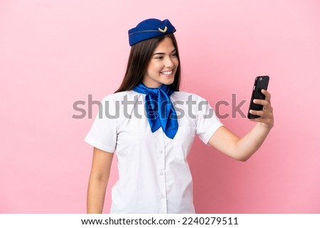 Airplane stewardess Brazilian woman isolated on pink background making a selfie