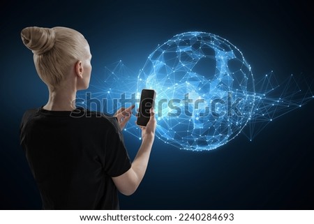 Back view of blonde young woman using cellphone with glowing polygonal sphere on blurry dark background. Futuristic technology wireframe mesh polygonal element.