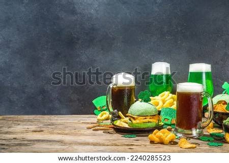 St Patrick`s holiday party invitation, bar menu background. Irish St Patrick`s day beer, ale glasses, snacks, appetizer, green burger, wooden bar table with shamrock, clover, coins, leprechaun hat