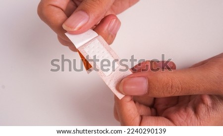 Opening Band Aid with two hands. Suitable for health theme designs, Close Up Photo. White Background.