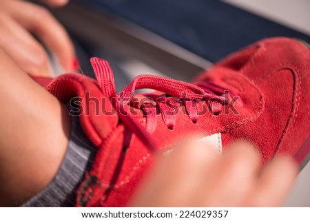 Selective focus on the legs of the woman wearing red jogging shoes putting right at it Royalty-Free Stock Photo #224029357