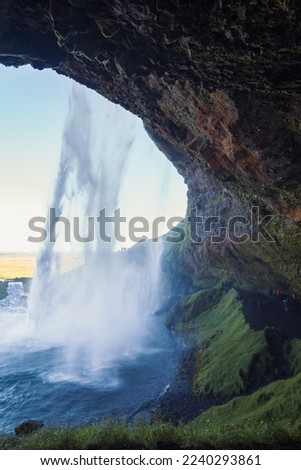 Cave under wonderful waterfall landscape photo. Beautiful nature scenery photography with valley on background. Idyllic scene. High quality picture for wallpaper, travel blog, magazine, article