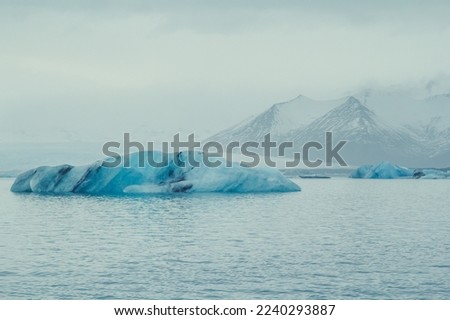 Striped iceberg floating in sea landscape photo. Beautiful nature scenery photography with mountains on background. Idyllic scene. High quality picture for wallpaper, travel blog, magazine, article