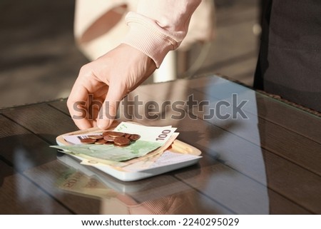 Waitress taking payment for order from wooden table at outdoor cafe, closeup. Leave tip Royalty-Free Stock Photo #2240295029