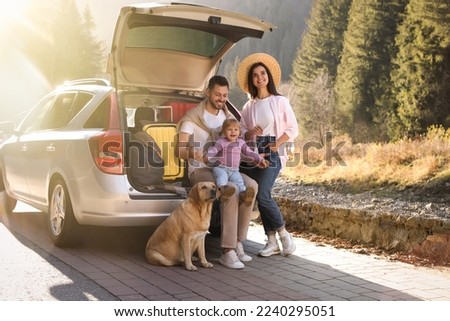 Parents, their daughter and dog near car outdoors. Family traveling with pet Royalty-Free Stock Photo #2240295051