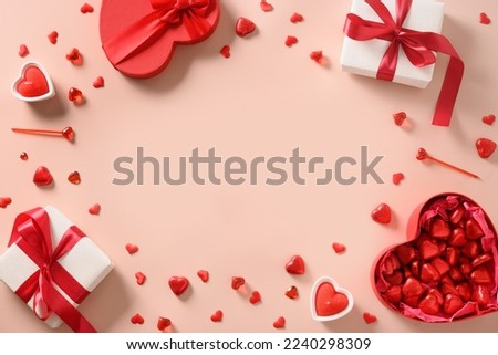 Valentine's day greeting card with red gifts, hearts chocolate sweets and candles on pink background. View from above. Copy space.