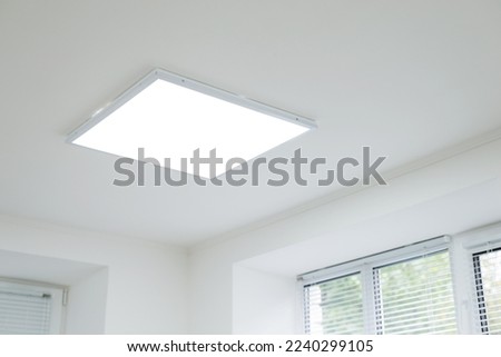Suspended ceiling with modern LED lighting. Turned on lamps on the ceiling in office of white colours Royalty-Free Stock Photo #2240299105
