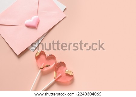 Valentine's day card with envelope and pink lollipops as heart on pink background. View from above. Copy space.