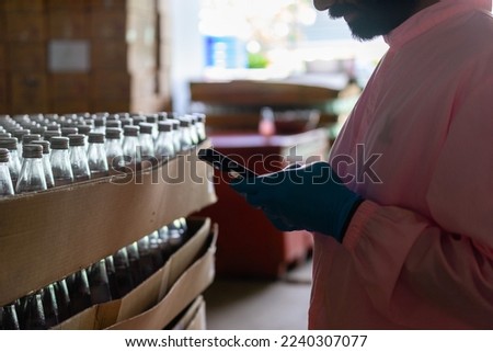 A beverage factory worker is texting from a mobile phone. read messages on cell phone