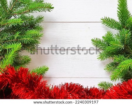 Red tinsel and green fir tree on white wooden background, winter flat lay. Copy space, cosmetic product advertising backdrop. Empty place to display product. Royalty-Free Stock Photo #2240309197