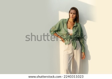 Fashionable woman posing over wite background.  Casual outfit. Green linen blouse . white crop top and pants. Full lenght.  Royalty-Free Stock Photo #2240311023
