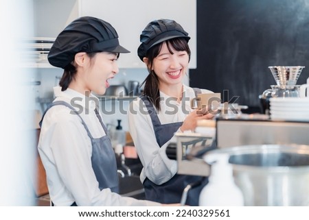 A woman working part-time in a restaurant happily learning about her duties Royalty-Free Stock Photo #2240329561