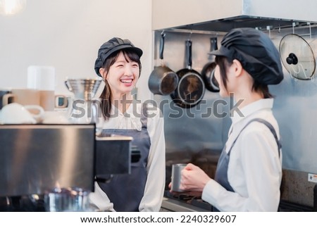 A woman working part-time in a restaurant happily learning about her duties Royalty-Free Stock Photo #2240329607