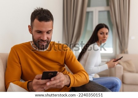 Jealous suspicious mad wife arguing with obsessed husband holding phone texting cheating on cellphone, distrustful girlfriend annoyed with boyfriend mobile addiction, distrust social media dependence Royalty-Free Stock Photo #2240350151