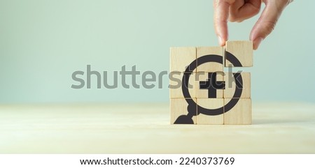 Annual health check up, healthcare medical, health insurance  concept. Magnifying glass and medical icons on wooden cube blocks. 