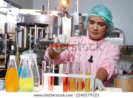 Indian female food engineer test tubes to sample beverage products in a juice beverage factory. Food and beverage quality and safety testing concepts Factory product production process Royalty-Free Stock Photo #2240379523