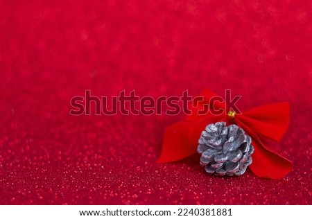 Pine cone and red bow on red glitter background, Christmas and New Year greeting card, selective focus, copy space for text