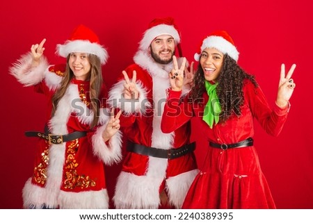 brazilian friends with christmas clothes, santa claus. peace and love, pose for photo.